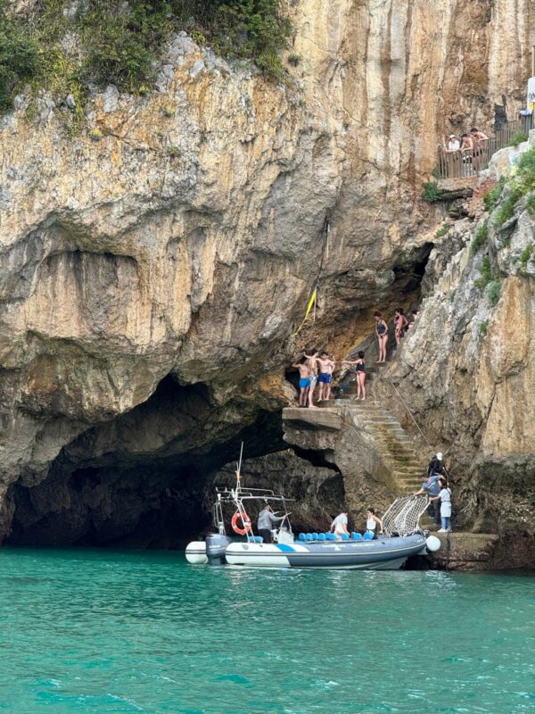 Barco de Taxi Express Faro recogiendo turistas en las escaleras del Faro del Caballo en Santoña, Cantabria, durante una excursión marítima.