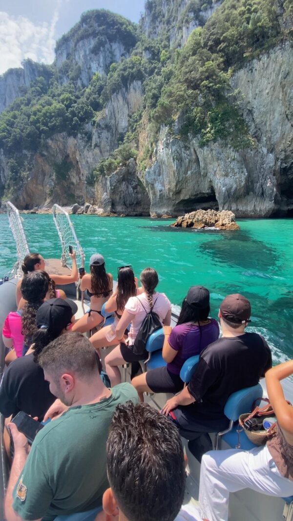 Recorrido en barco de regreso a Santoña desde el Faro del Caballo con Taxi Express Faro, turistas disfrutando de aguas turquesas y acantilados en Cantabria.