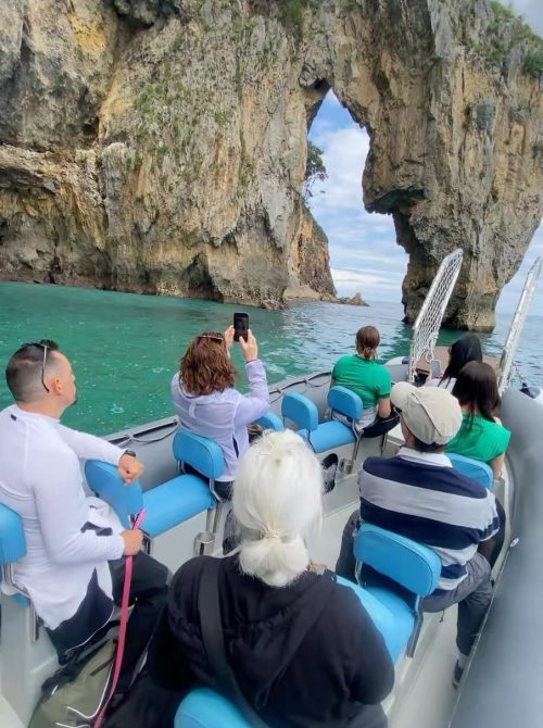 Pasajeros disfrutando de una excursión en barco con Taxi Express Faro frente al arco natural del Faro del Caballo en Santoña, Cantabria.