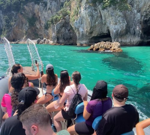 Recorrido en barco de regreso a Santoña desde el Faro del Caballo con Taxi Express Faro, turistas disfrutando de aguas turquesas y acantilados en Cantabria.